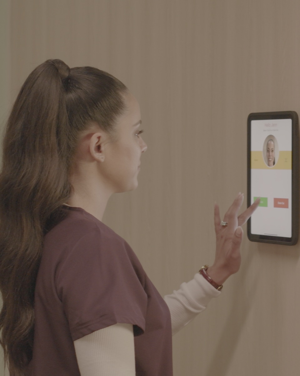 A clinician clocking in at a wall-mounted iPad running the NoahFace timeclock app